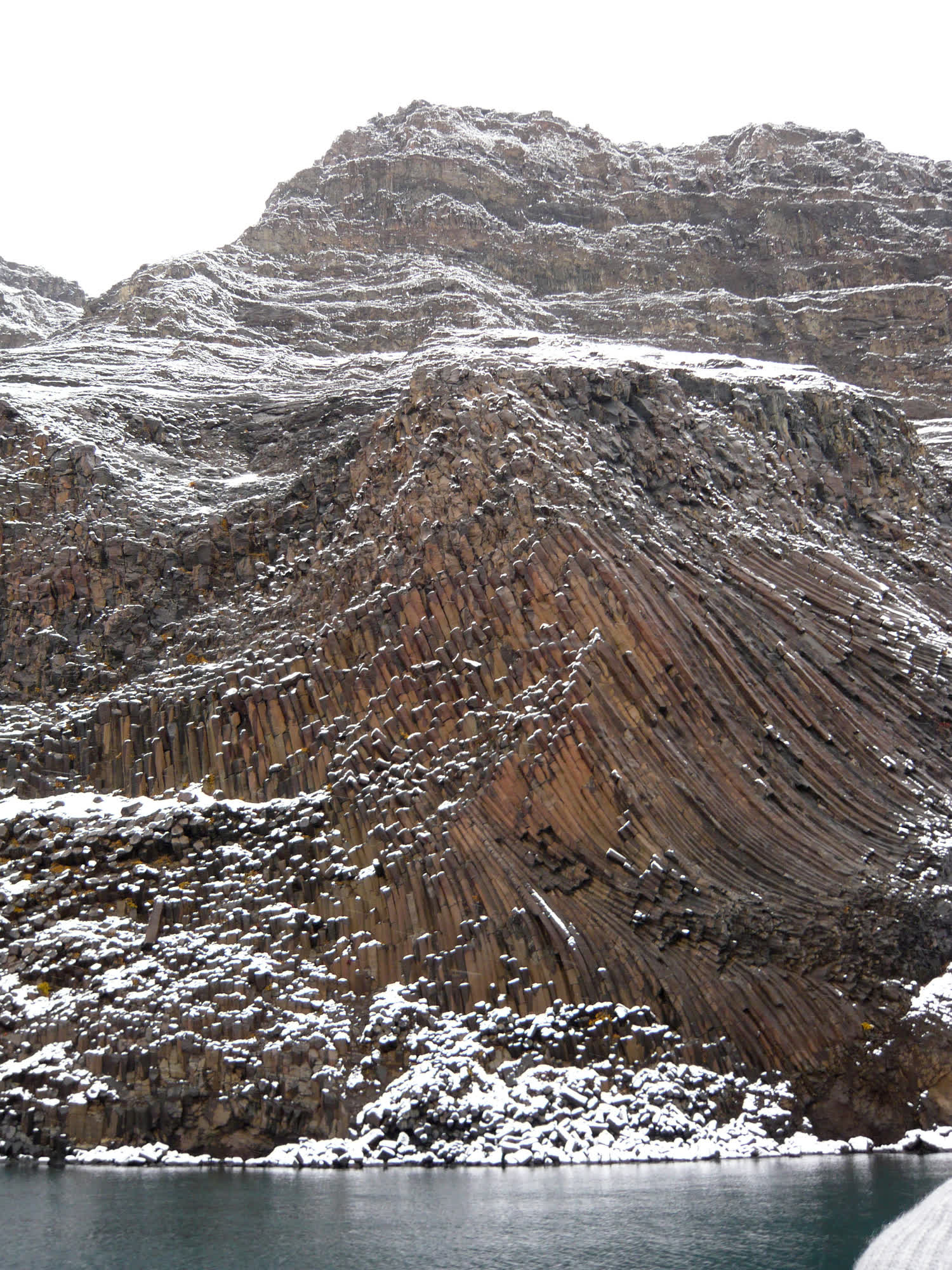 Steilküste aus geschichtetem Basalt über dem Wasser eines Fjords